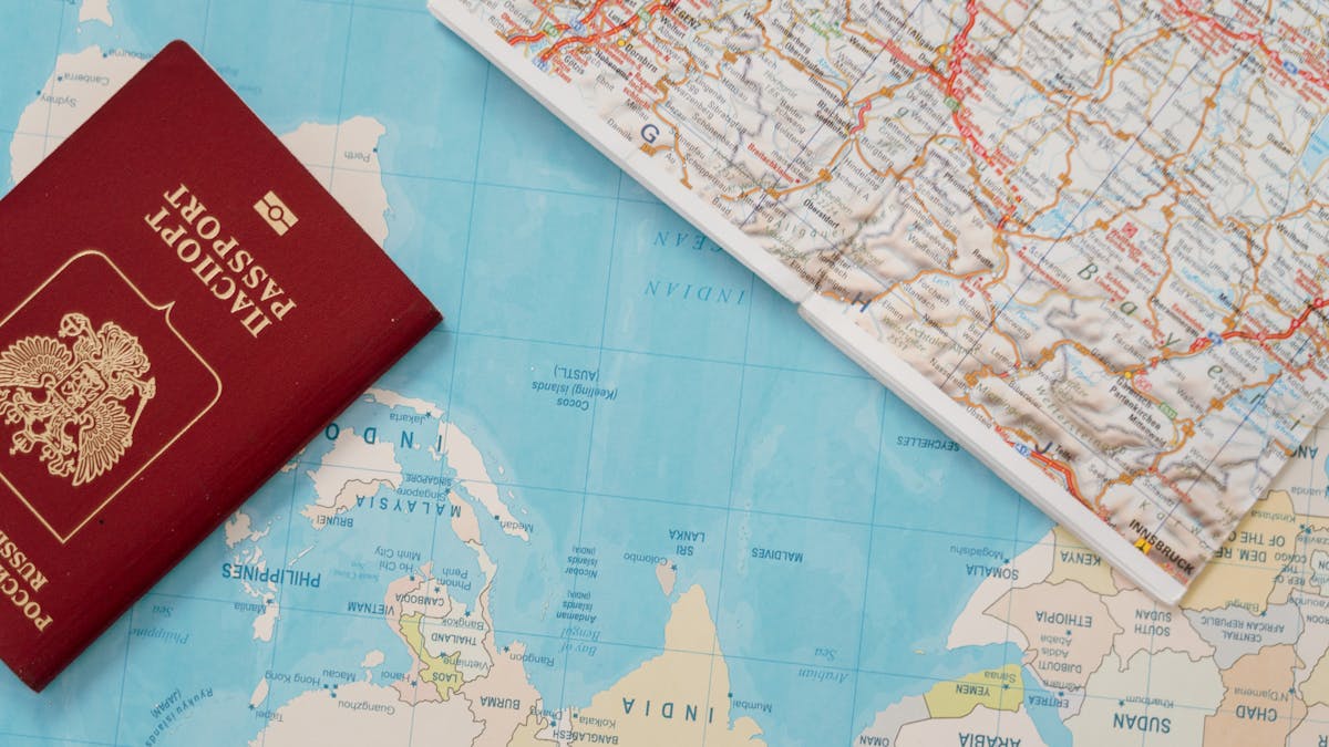 A passport and travel documents laid out on a world map, representing international travel rights for refugees holding Convention Travel Documents